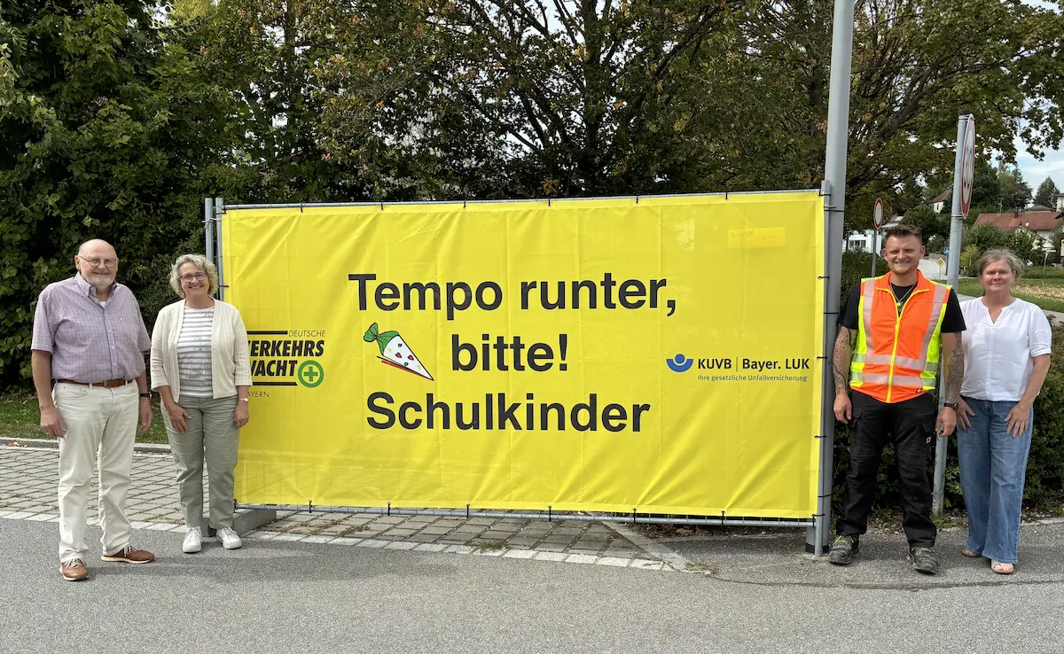 Übergabe eines gelben Verkehrssicherheitsbanners mit der Aufschrift „Tempo runter, bitte! Schulkinder“ an einem Straßenrand in Steinach. Das Banner wirbt für mehr Sicherheit von Schulkindern im Straßenverkehr.